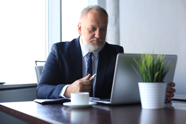 Photo mature businessman working on computer in modern office.