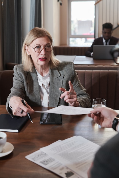 Фото Зрелая бизнес-леди консультируется с мужчиной о документах во время встречи в кафе