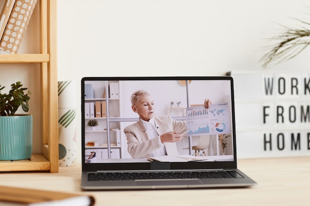 Photo mature businesswoman pointing at charts in her hand and talking about financial situation during online business conference