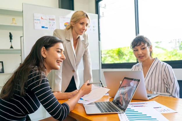 Mature businesswoman talking to young businesswoman at desk in office