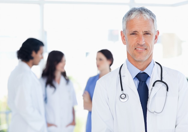 Mature and calm doctor standing upright in front of his medical interns