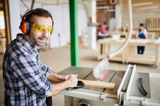 Carpentiere maturo che utilizza le macchine nell'officina