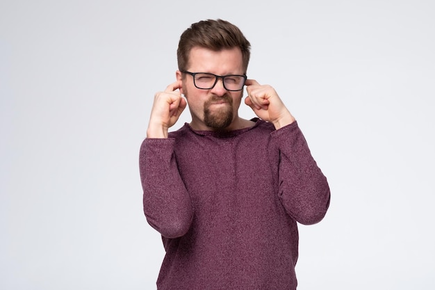 Mature caucasian man covering his ear does not want to listen to the latest gossip