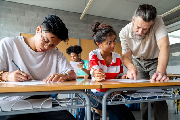 Photo mature caucasian  teacher with beard assisting asian high school girl student with task education