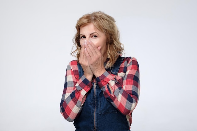 Mature caucasian woman covering her mouth with hands