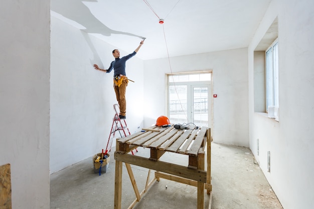 Foto stuccatore maturo dell'appaltatore che lavora all'interno