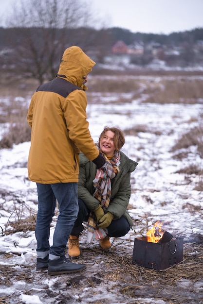 写真 キャンプでの成熟したカップルは、野生の冬の休暇で幸せな家族を発射します雪の自然の中で笑顔の中年の男性と女性または一緒に駐車家族の季節の休暇のコンセプト