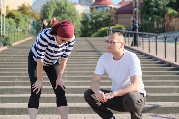 Mature couple in city near the stairs, middle-aged man and woman in sportswear 