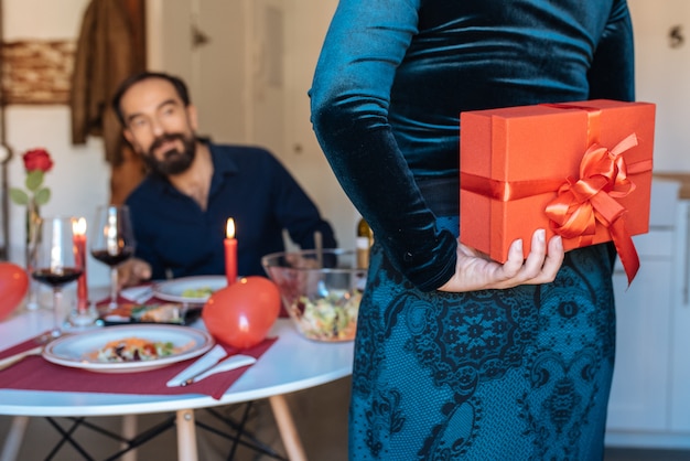 Mature couple having a romantic dinner at home for valentines day with surprise gift 
