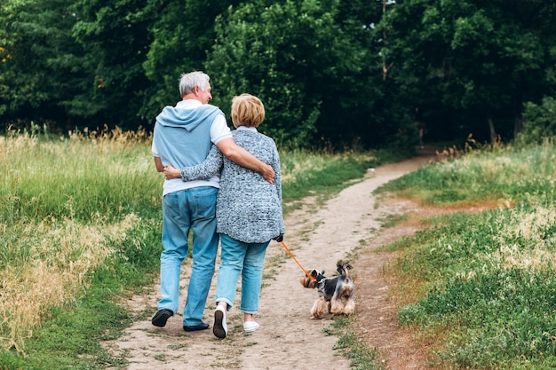 Una coppia matura sta camminando con un cane in un parco