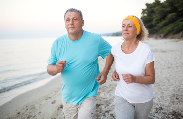 Photo mature couple jogging on shore at beach