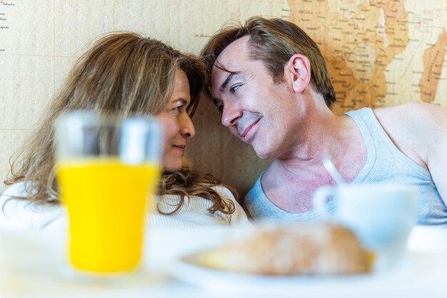 Coppia matura innamorata a letto, con un vassoio con colazione. foto di alta qualità