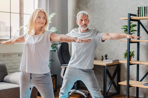 Coppia matura che pratica yoga e si esibisce in posa di yoga guerriero insieme