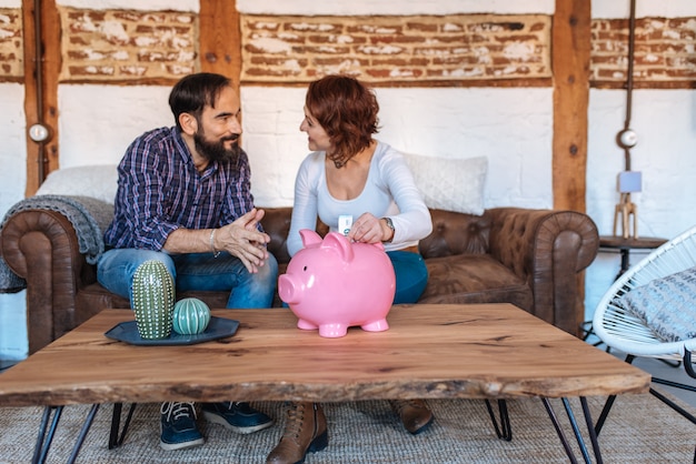 Photo mature couple relaxed at home in the sofa saving money on the piggy bank