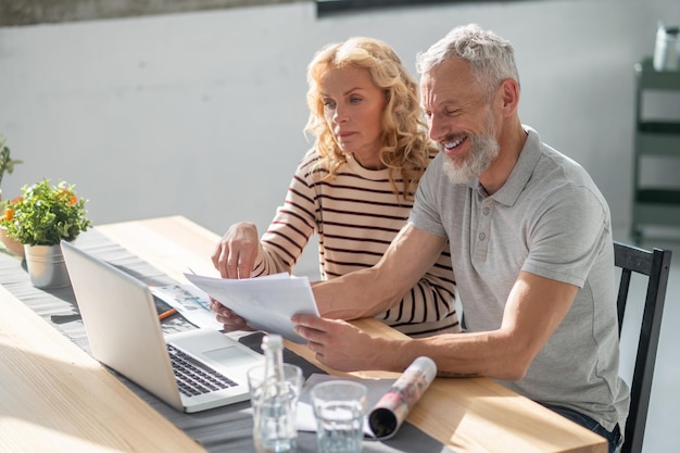 A mature couple scrutinizing the papres and searching internet