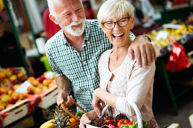 Mature couple shopping vegetables and fruits on the market. Healthy diet.