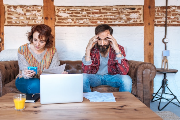 Mature couple sitting at home looking at their finance problems