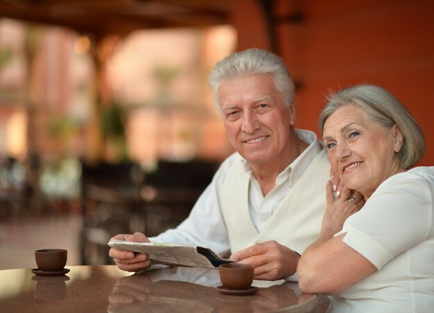 Mature couple sitting with laptop in hotel with tea