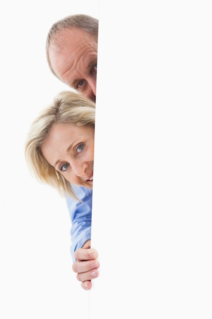 Photo mature couple smiling behind wall