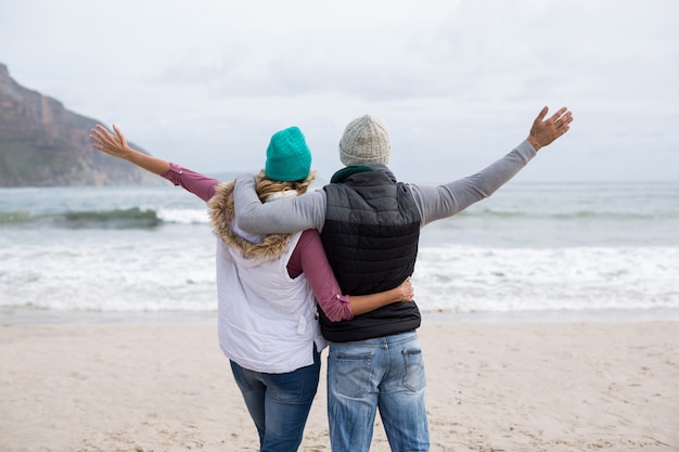 Mature couple standing with arms outstretched