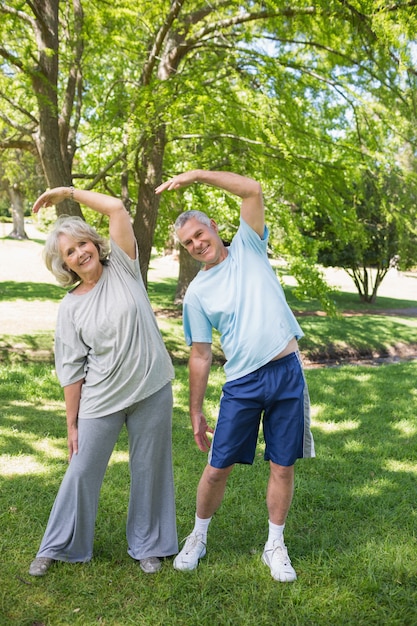 Mature couple stretching hands at park