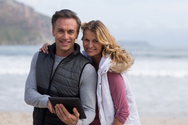 Photo mature couple using digital table on the beach