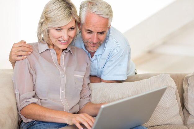 Mature couple using laptop on sofa