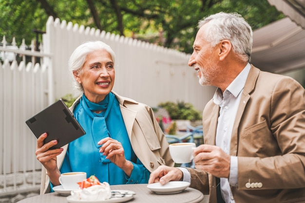 Mature couple with tablet sitting in a restaurant