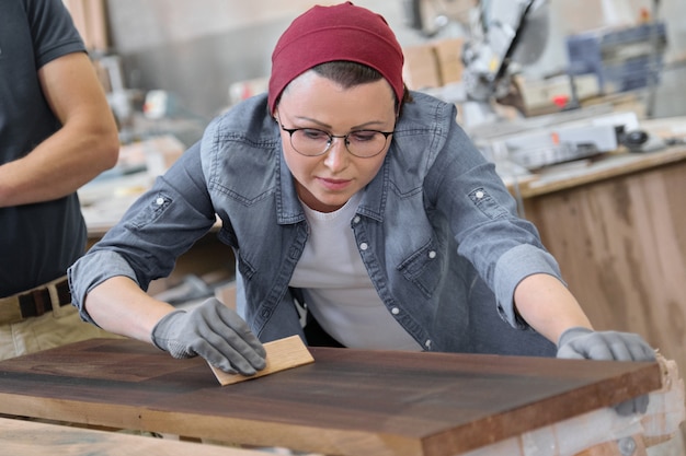 Mature craftswoman working in woodshop.