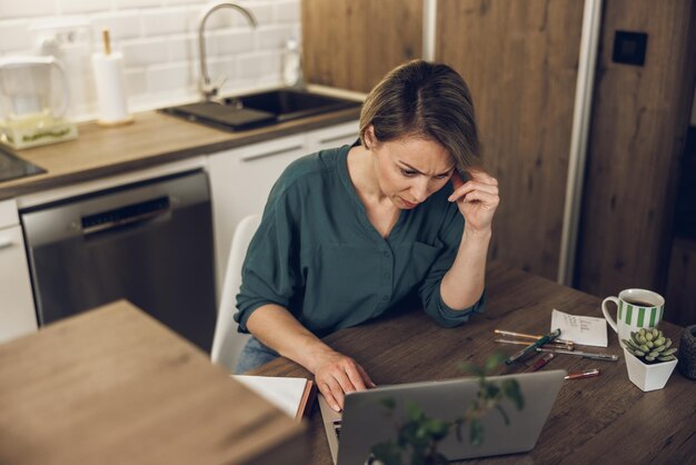 Mature designer woman looking thoughtful while working from her home office.