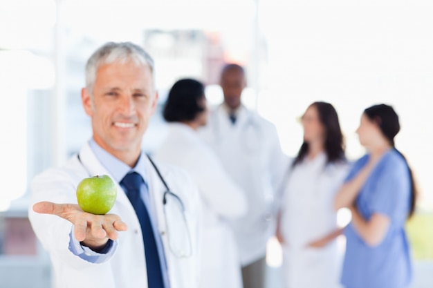 Mature doctor holding a green apple