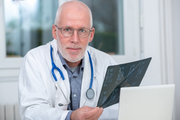 Mature Doctor looking at an x-ray in an office