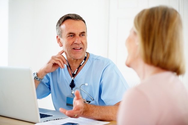 Mature doctor talking with female patient sitting at desk Portrait of a mature doctor talking with female patient sitting at desk