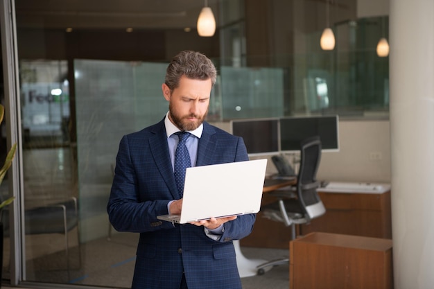 Mature entrepreneur man working online on wireless laptop outside the office business online