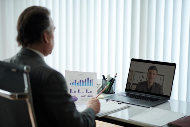 mature entrepreneur taking to coworker from another office in online meeting