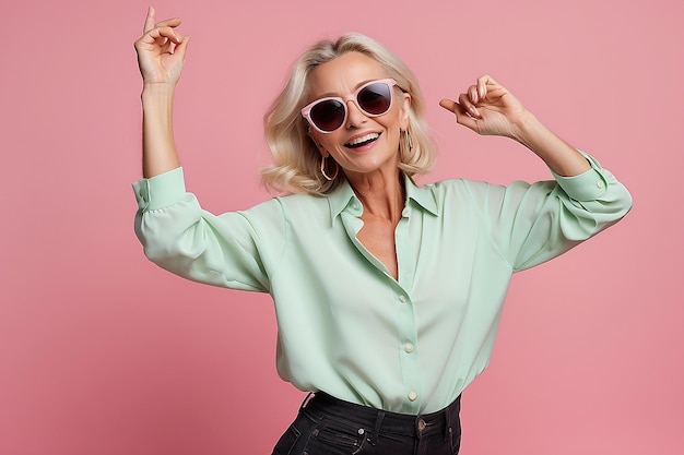 Mature european woman wearing sunglasses dancing on camera isolated over pink background