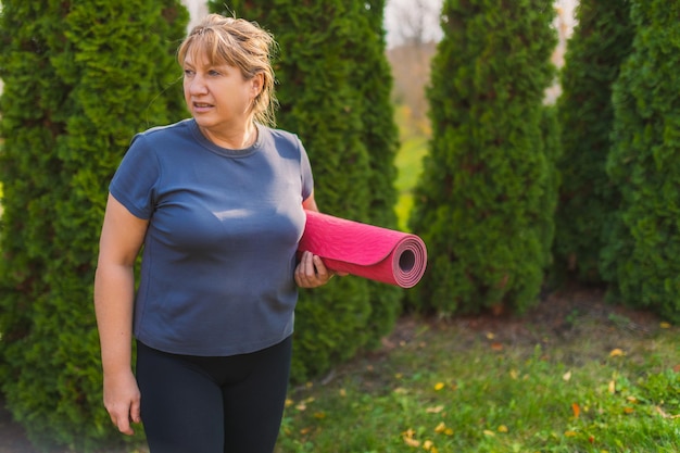 Mature female on outdoor yoga retreat walking along path\
through campsite