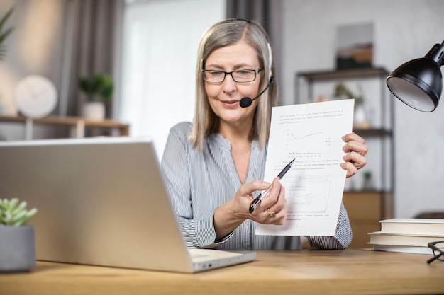 Mature female talking with colleagues via computer webcam