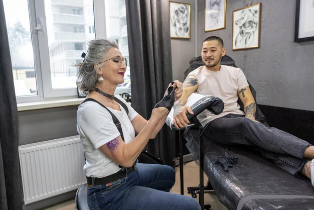 Mature female tattoo master working with the customer