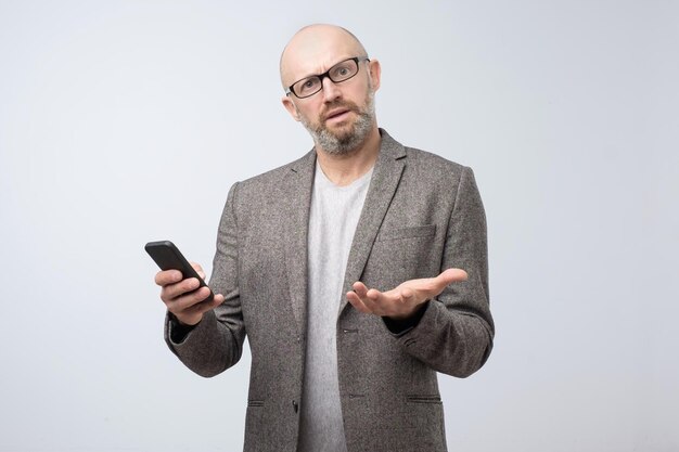 Mature frowning disgusted man surfing smartphone in dislike