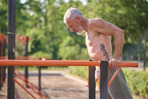 Зрелый седой мужчина тренируется в парке