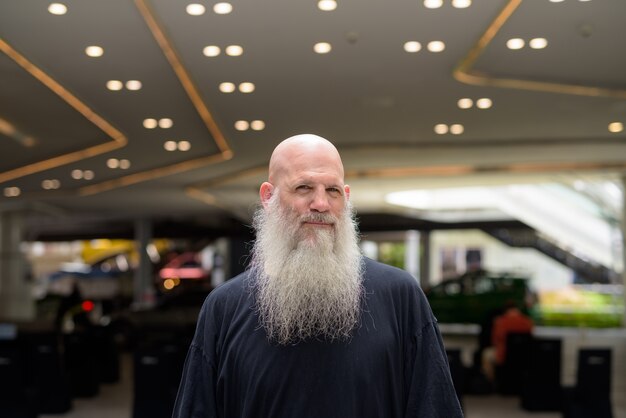 Mature handsome bald bearded man in the city outdoors