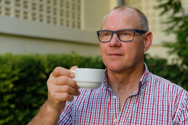 Mature handsome man drinking coffee in the streets outdoors