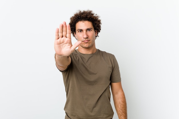 Mature handsome man standing with outstretched hand showing stop sign, preventing you.