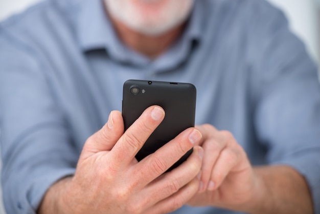 Mature handsome  man using smartphone at home