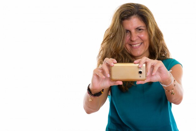 mature happy woman smiling while taking picture with her mobile phone