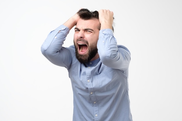 Mature hispanic man pulling his hair in hysteria having troubles at work