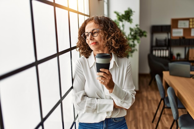 Photo mature hispanic woman working drinking a coffee at the office