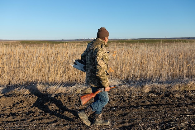 A mature hunter arranges stuffed decoy geese across the field