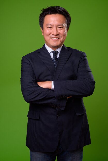 Mature Japanese businessman against green background